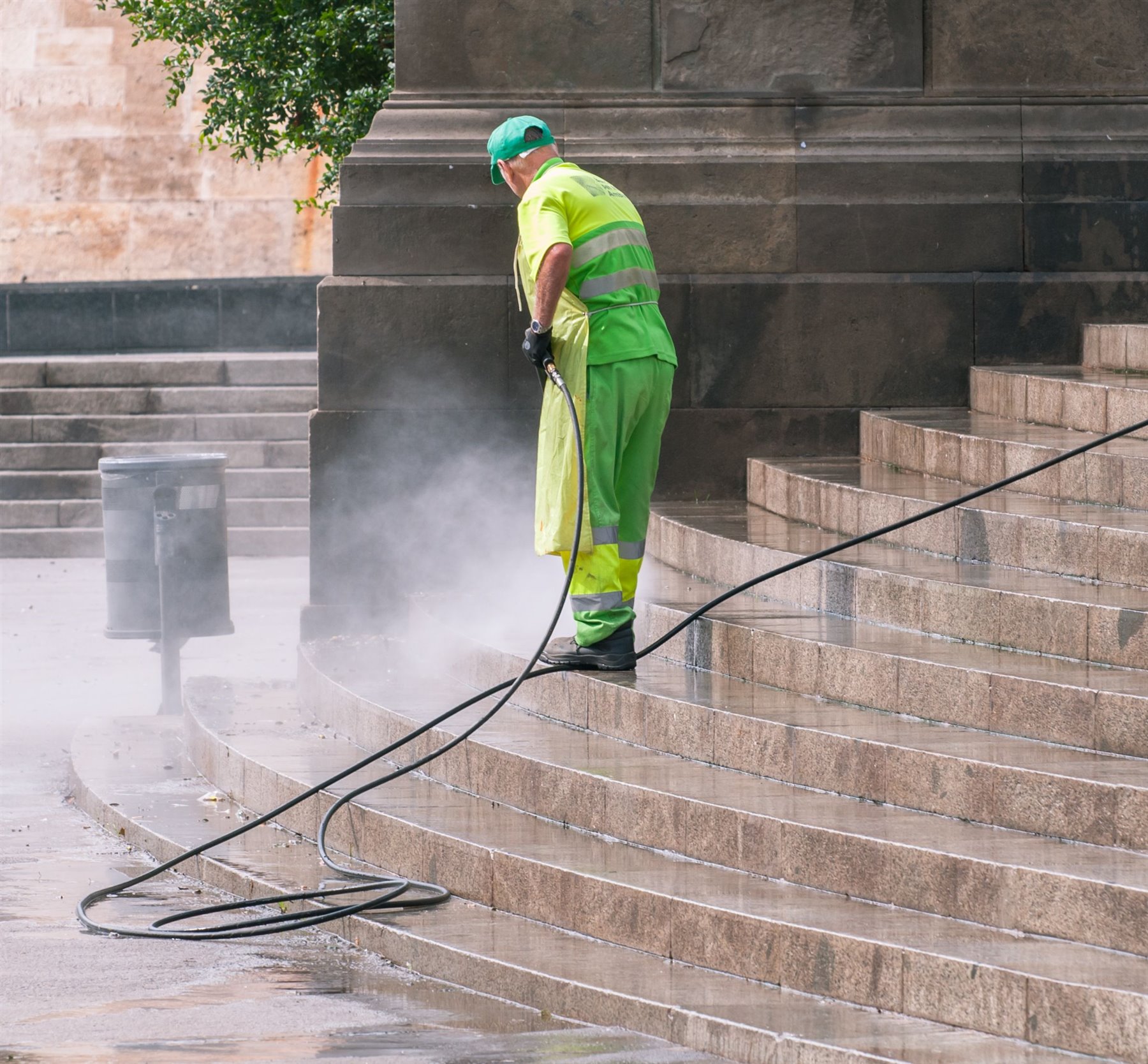 Worker pressure washing stone steps and outdoor paving