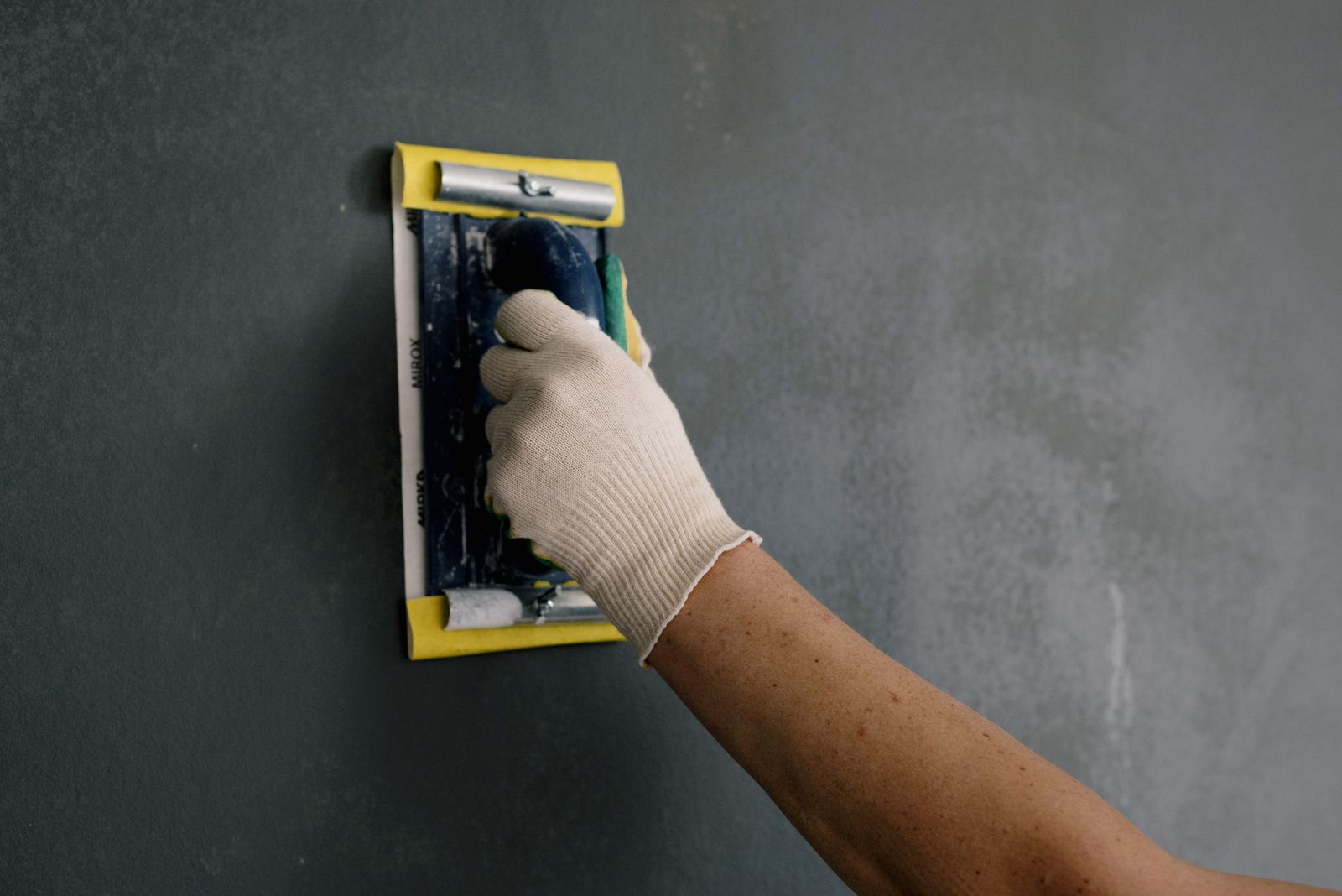 Spackle tool smoothing an apartment wall before repainting